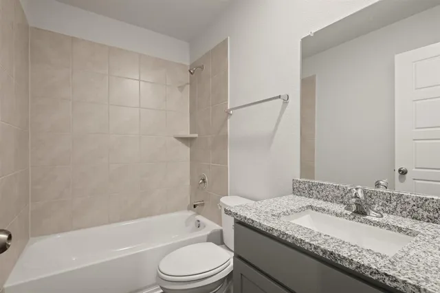a bathroom with a granite countertop sink toilet mirror and bathtub