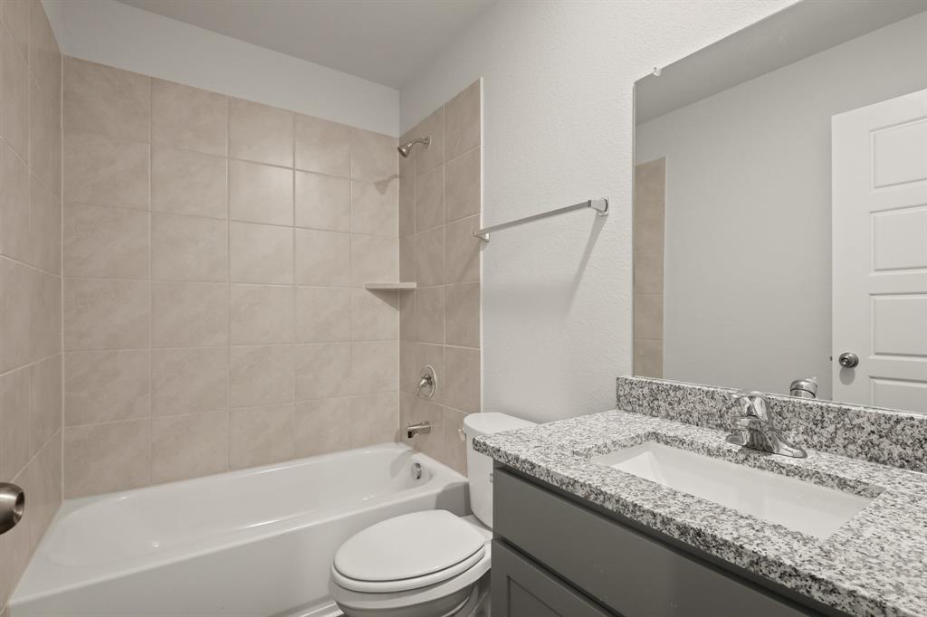 3117 Harmony Way Cleburne, TX 76031 - Photo 18 of 20 a bathroom with a granite countertop sink toilet mirror and bathtub