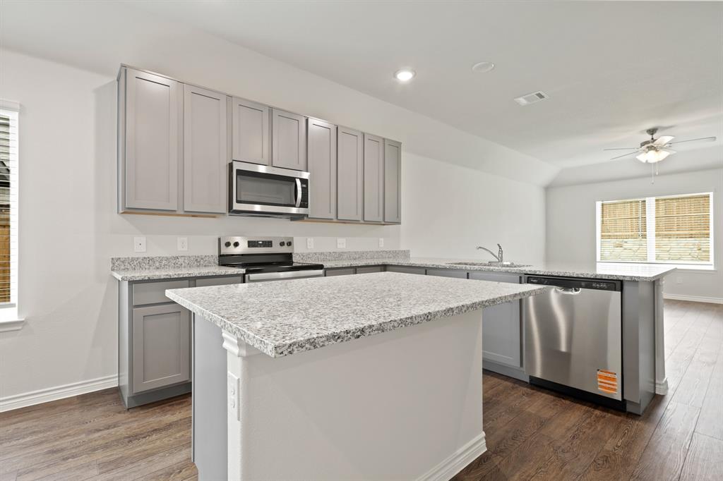 3117 Harmony Way Cleburne, TX 76031 - Photo 4 of 20 a kitchen with stainless steel appliances granite countertop a stove a sink and a microwave