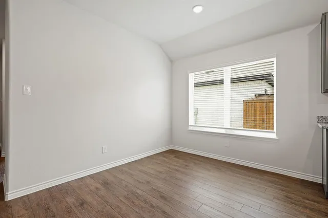 an empty room with wooden floor and a window
