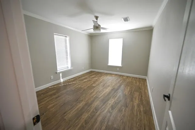 a view of empty room with wooden floor and fan