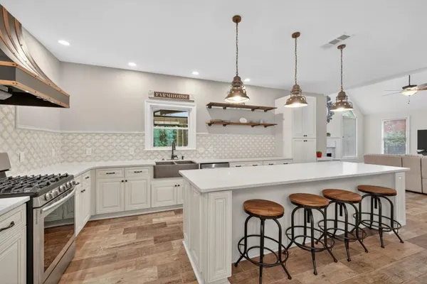 a large kitchen with kitchen island a stove a sink a dining table and chairs