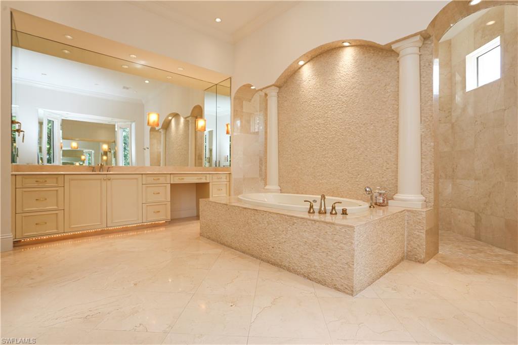 823 Cassena Road Naples, FL 34108 - Photo 27 of 50 a spacious bathroom with a tub a double vanity sink and mirror