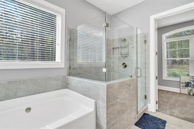 a spacious bathroom with a tub sink shower and mirror
