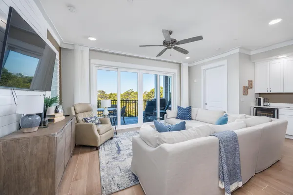 a living room with furniture large windows and wooden floor