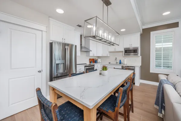 a kitchen with stainless steel appliances a table chairs and refrigerator