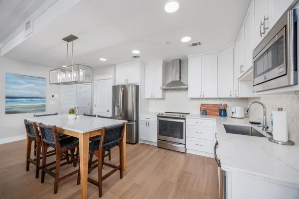 a kitchen with stainless steel appliances a dining table chairs stove refrigerator and cabinets