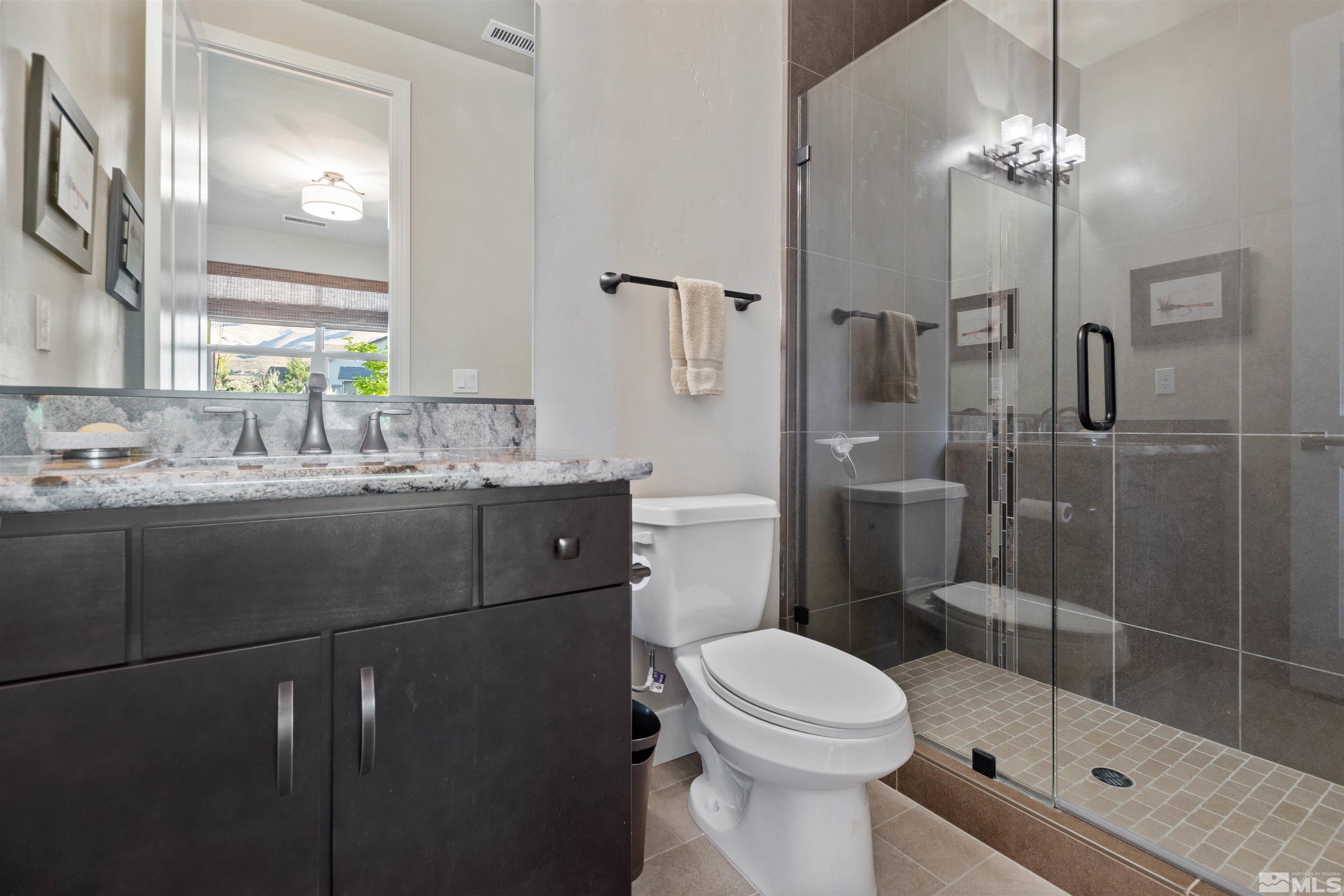 1575 Scott Valley Road Reno, NV 89523 - Photo 23 of 40 a bathroom with a toilet a sink a glass door shower and mirror