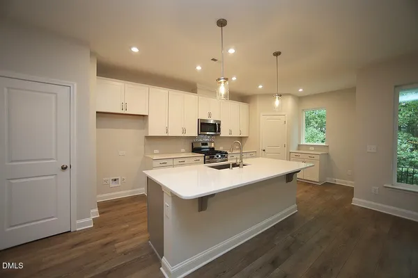 a kitchen with a sink a stove a refrigerator and white cabinets with wooden floor