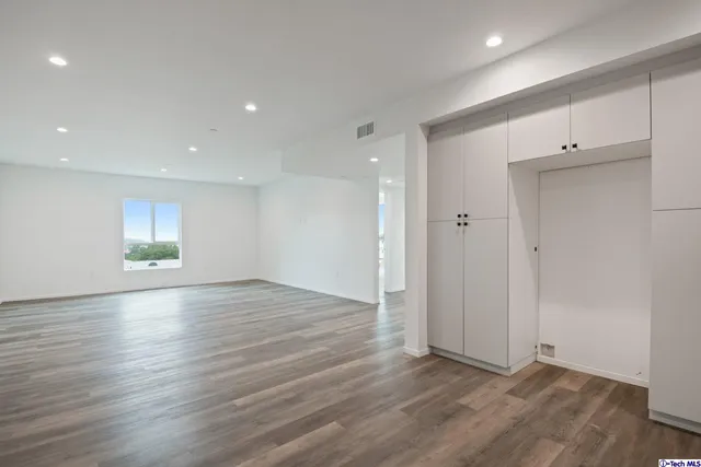 a kitchen with cabinets stainless steel appliances and wooden floor
