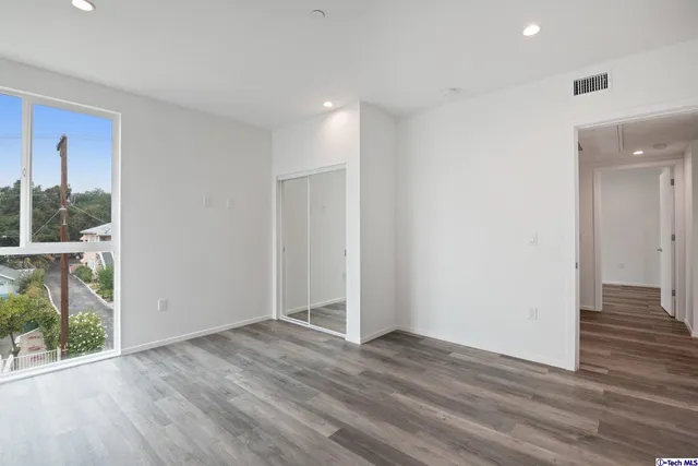 an empty room with wooden floor and windows