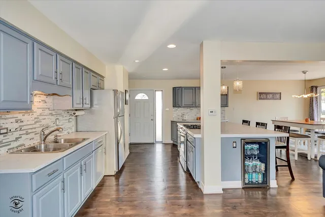 a kitchen with stainless steel appliances kitchen island granite countertop a refrigerator a sink a stove and white cabinets