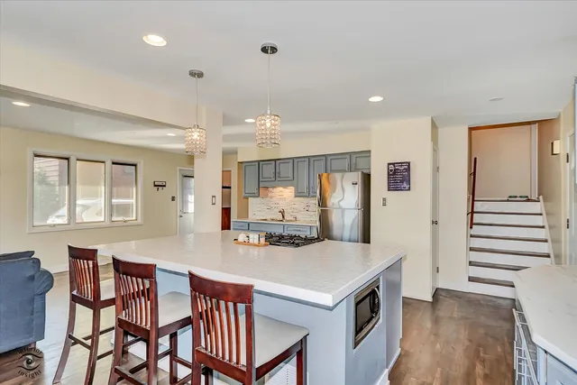 a kitchen with stainless steel appliances kitchen island granite countertop a kitchen island hardwood floor and a sink