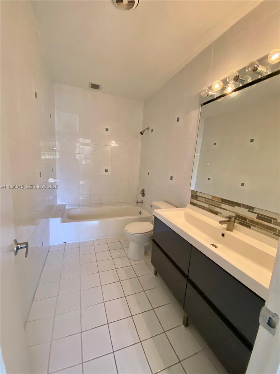 1101 Bay Drive Miami Beach, FL 33141 - Photo 62 of 69 a spacious bathroom with a granite countertop sink a toilet a mirror and vanity