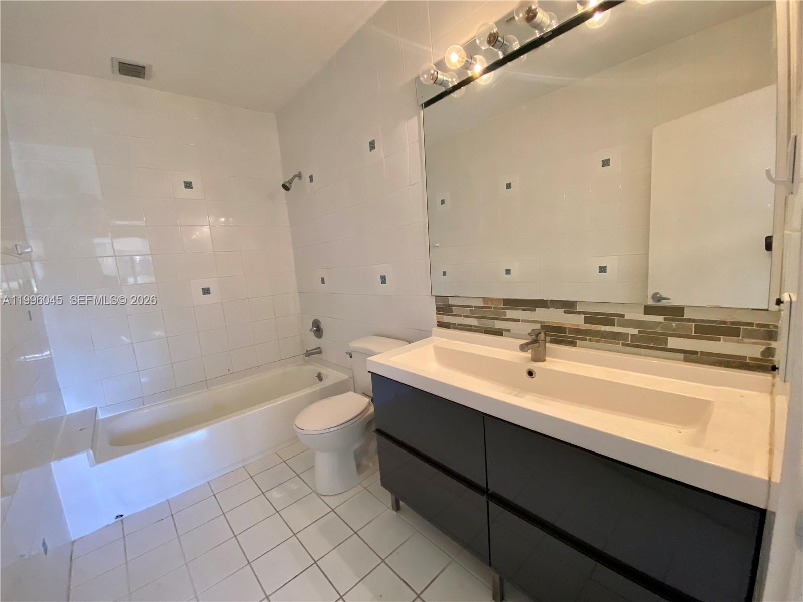 1101 Bay Drive Miami Beach, FL 33141 - Photo 63 of 69 a bathroom with a sink a toilet a mirror and bathtub