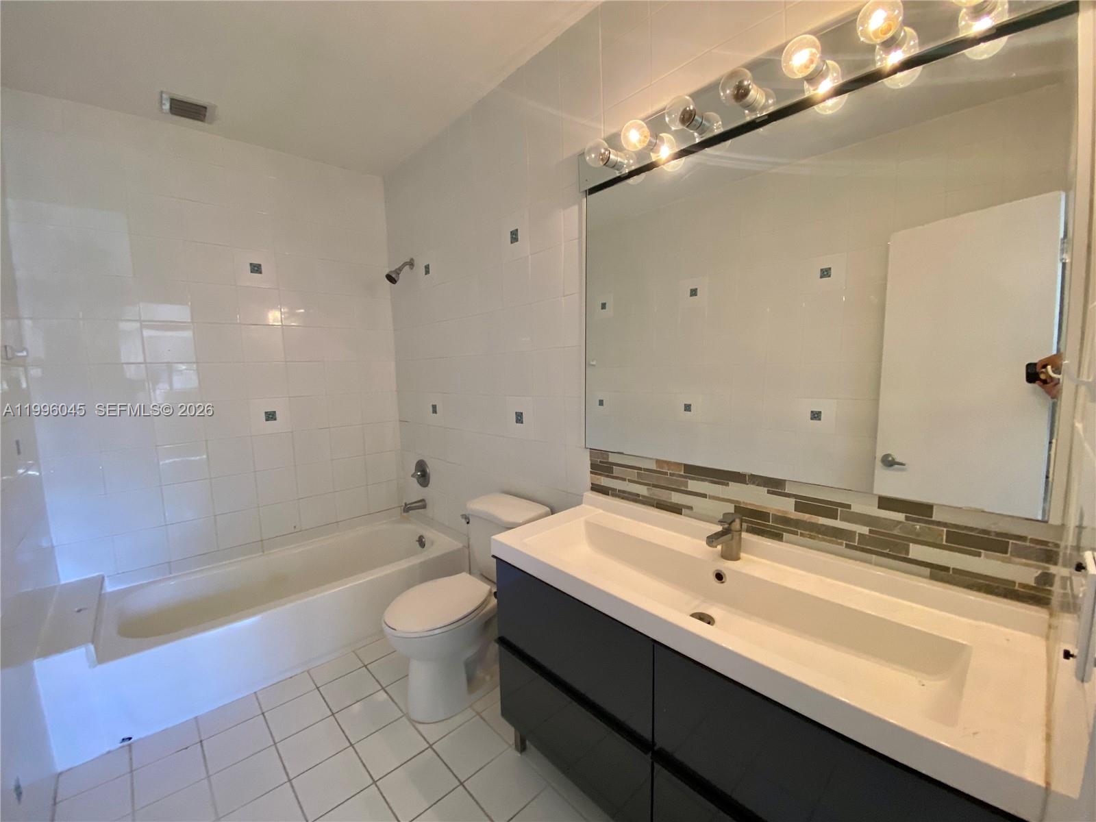 1101 Bay Drive Miami Beach, FL 33141 - Photo 66 of 69 a bathroom with a double vanity sink toilet mirror and bathtub
