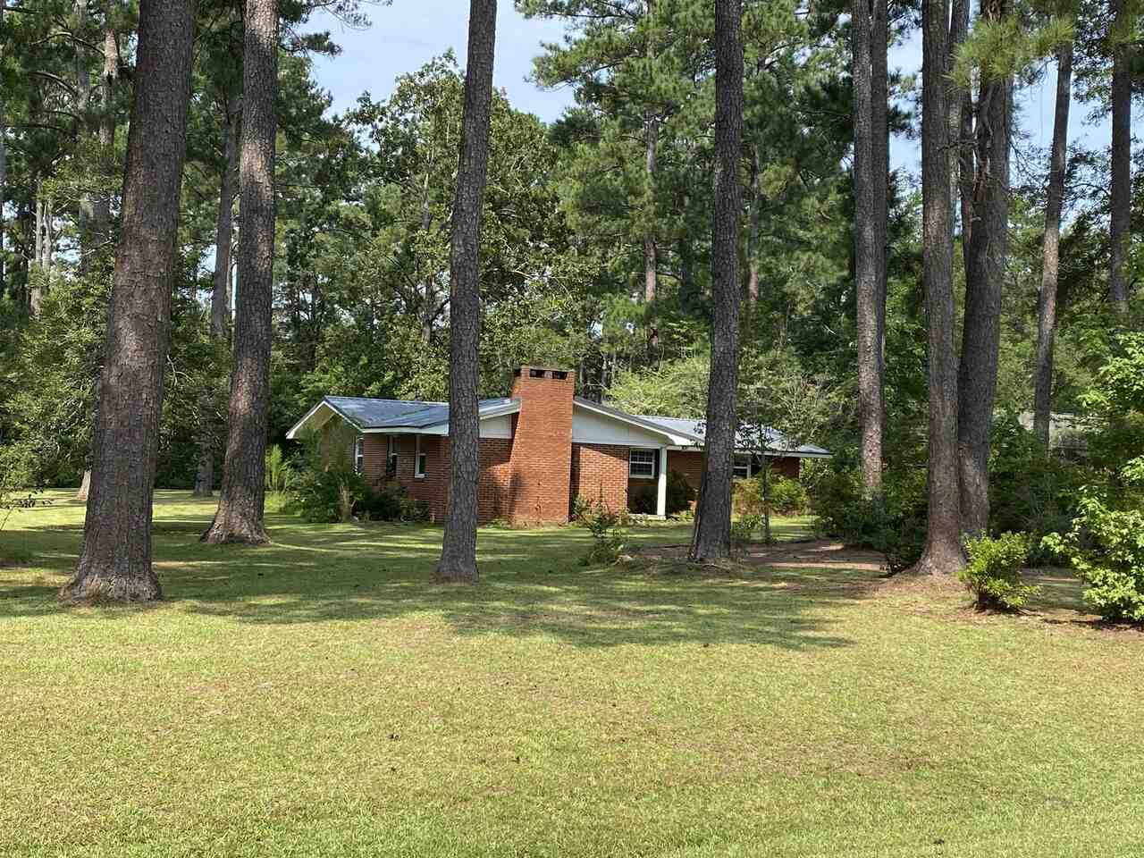 a view of a house with a yard and large trees
