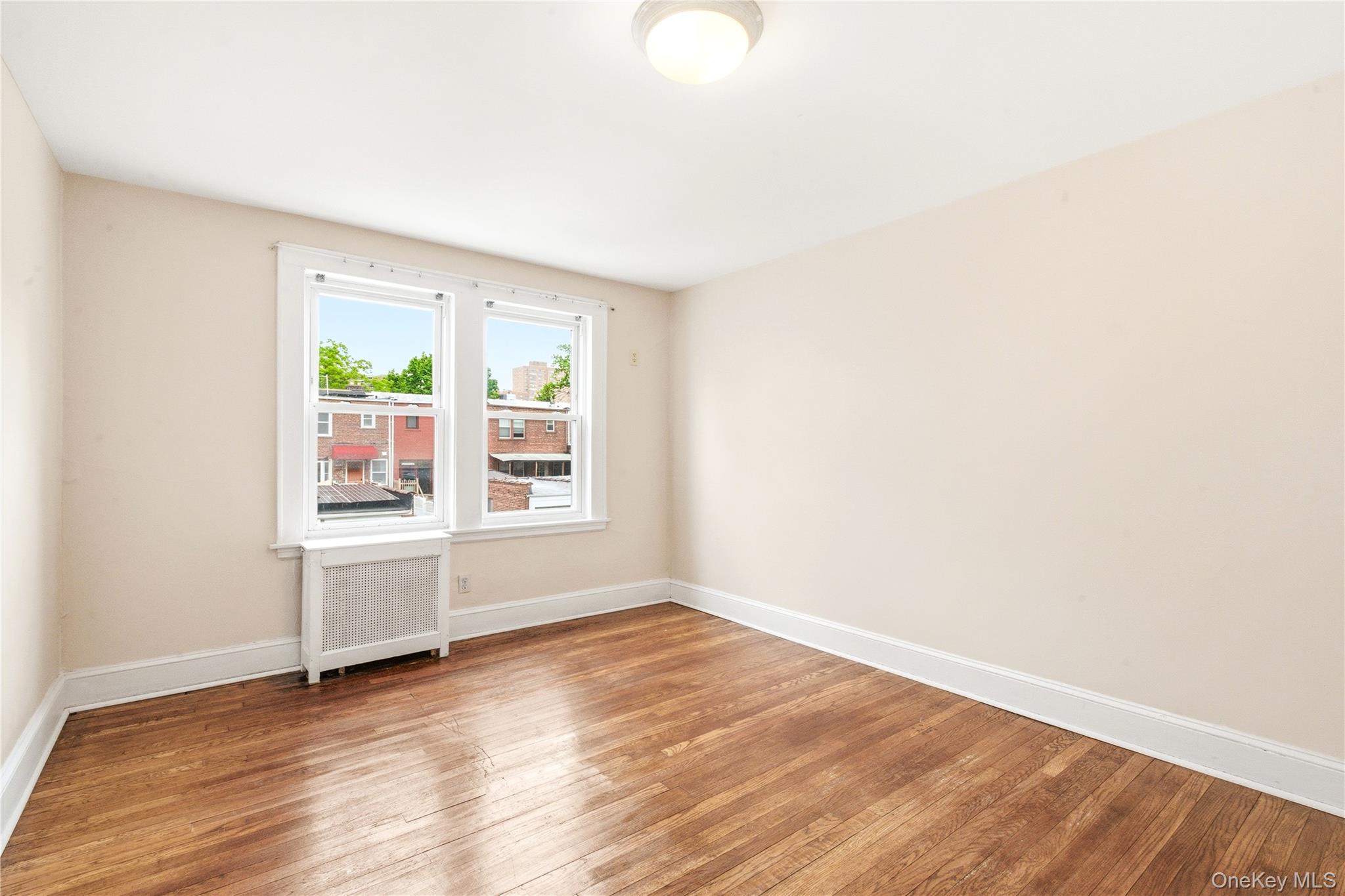 67-99 Exeter Street Queens, NY 11375 - Photo 14 of 28 an empty room with wooden floor and windows