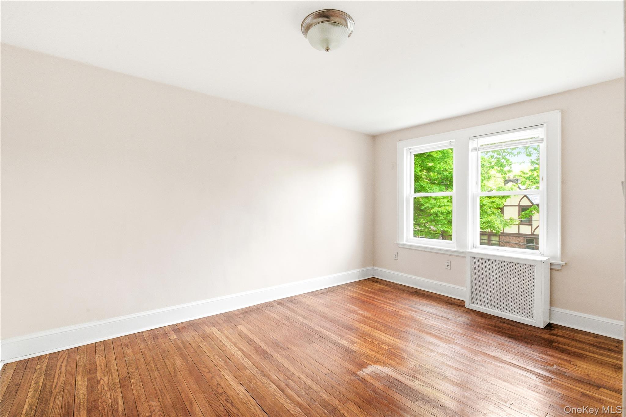 67-99 Exeter Street Queens, NY 11375 - Photo 17 of 28 an empty room with wooden floor and windows