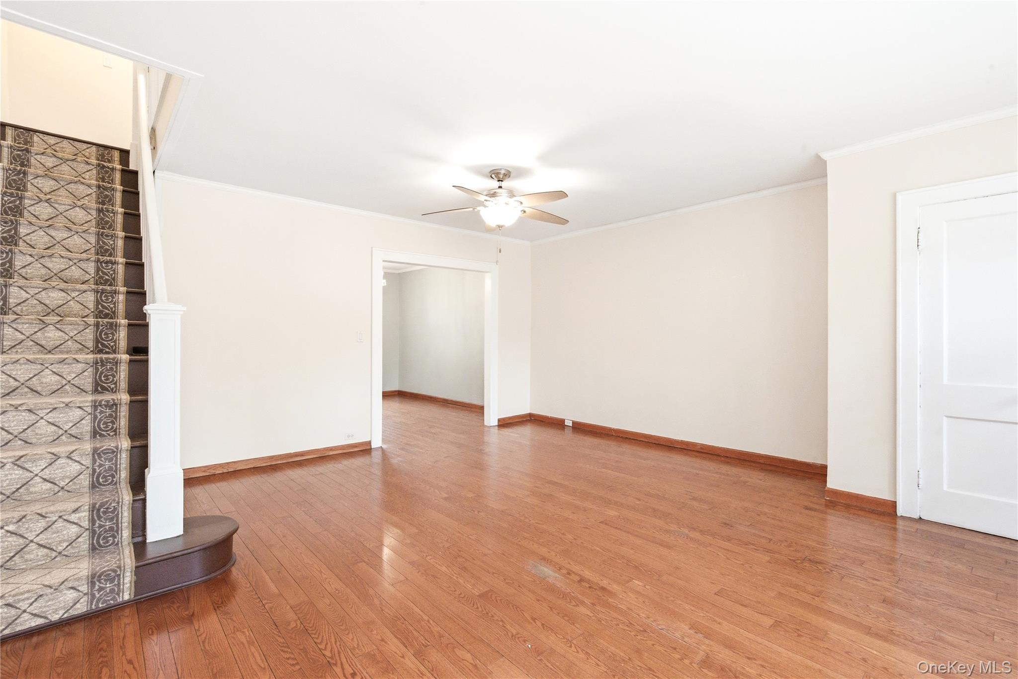 67-99 Exeter Street Queens, NY 11375 - Photo 7 of 28 an empty room with wooden floor chandelier fan and windows