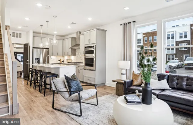 a kitchen with stainless steel appliances kitchen island granite countertop a refrigerator a stove a sink and white cabinets with wooden floor