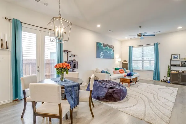 a dining room with wooden floor a chandelier a glass table and chairs