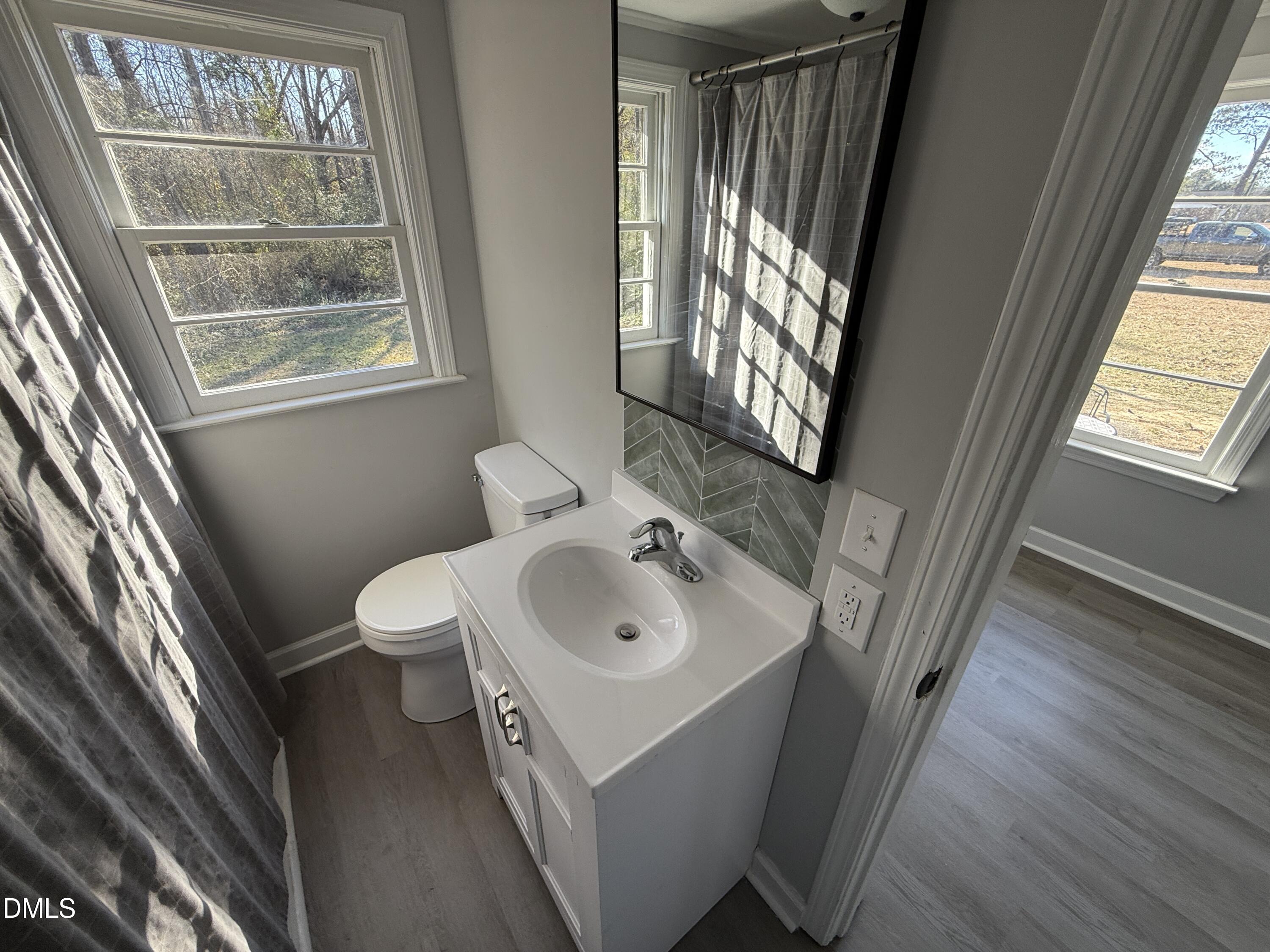 895 Stewart Road Four Oaks, NC 27524 - Photo 14 of 38 a bathroom with a sink a toilet a mirror and window