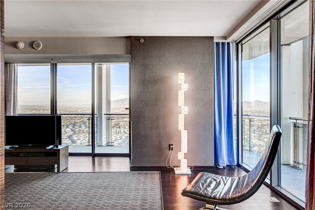 4381 West Flamingo Road, Unit 3002 Las Vegas, NV 89103 - Photo 52 of 59 Towering floor-to-ceiling windows frame expansive city and mountain views from this contemporary living space.
