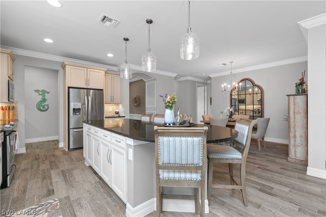 10832 Dennington Road Fort Myers, FL 33913 - Photo 1 of 34 a kitchen with stainless steel appliances kitchen island granite countertop a refrigerator a stove microwave and white cabinets with wooden floor