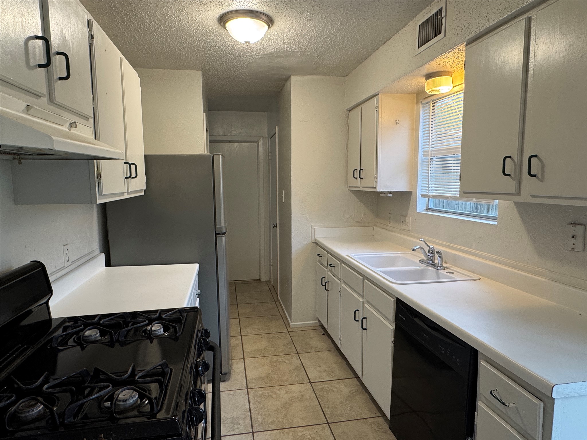 5810 Hammermill Run Austin, TX 78744 - Photo 3 of 10 Kitchen with light countertops, a textured ceiling, a sink, visible vents, and black appliances