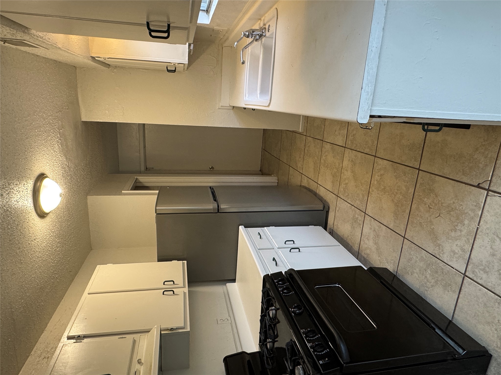 5810 Hammermill Run Austin, TX 78744 - Photo 4 of 10 Kitchen featuring white cabinetry, a sink, stove, light tile patterned floors, and freestanding refrigerator