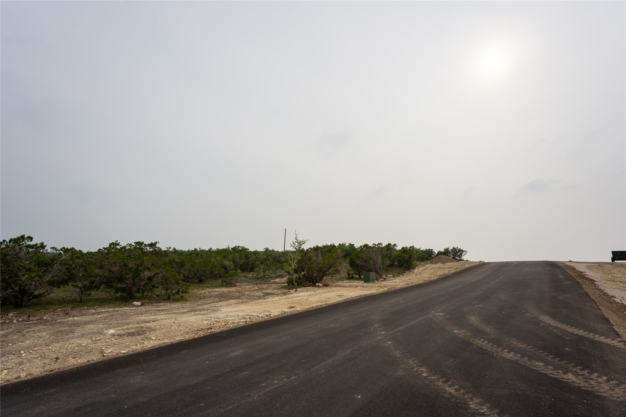 Lot 5 Ranch Road 165 Dripping Springs, TX 78620 - Photo 10 of 12 Paved road traversing undeveloped land with established vegetation