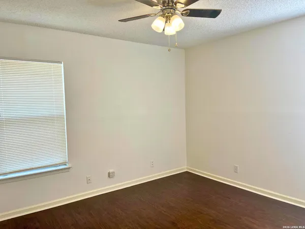 an empty room with wooden floor closet and fan