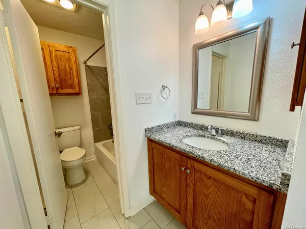 a bathroom with a granite countertop sink toilet and mirror