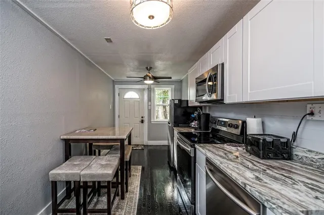 a kitchen with a table chairs microwave and cabinets