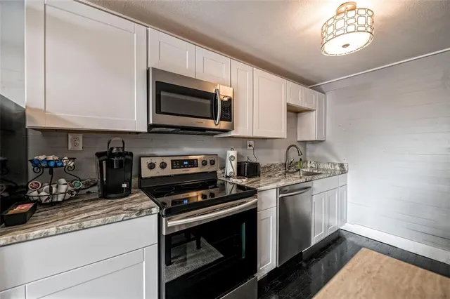 a kitchen with stainless steel appliances granite countertop a stove a microwave and a sink