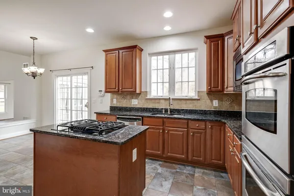 a kitchen with stainless steel appliances granite countertop a refrigerator a sink dishwasher a stove with wooden cabinets and floor