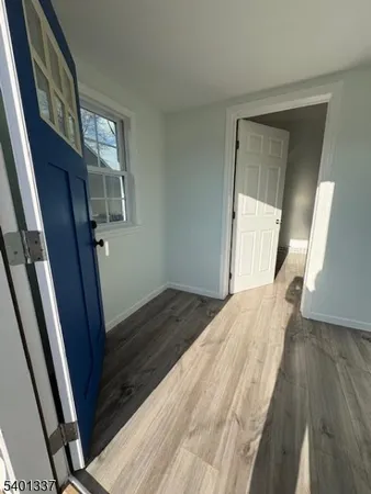 a view of an empty room with wooden floor and stairs