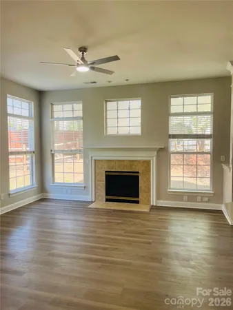 an empty room with wooden floor fireplace and windows