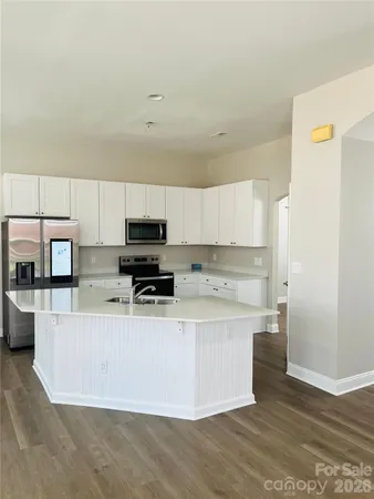 a kitchen with stainless steel appliances a sink a stove a microwave a sink a refrigerator and cabinets