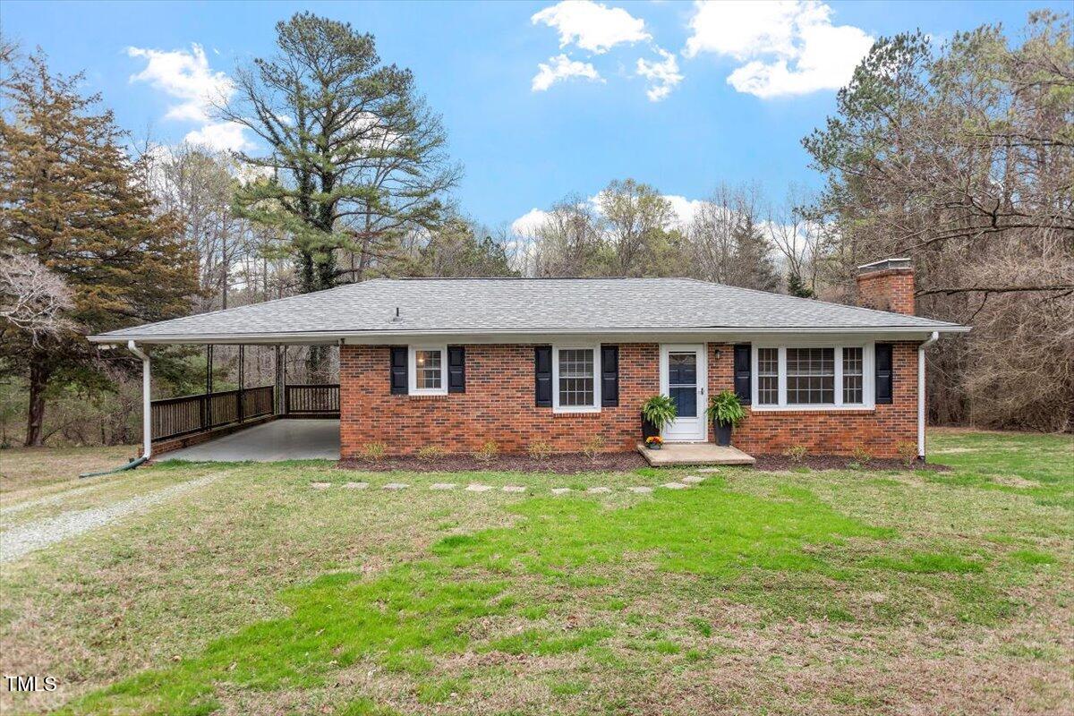 3402 Pat Tilley Road Bahama, NC 27503 - Photo 1 of 32 a front view of a house with a garden and trees