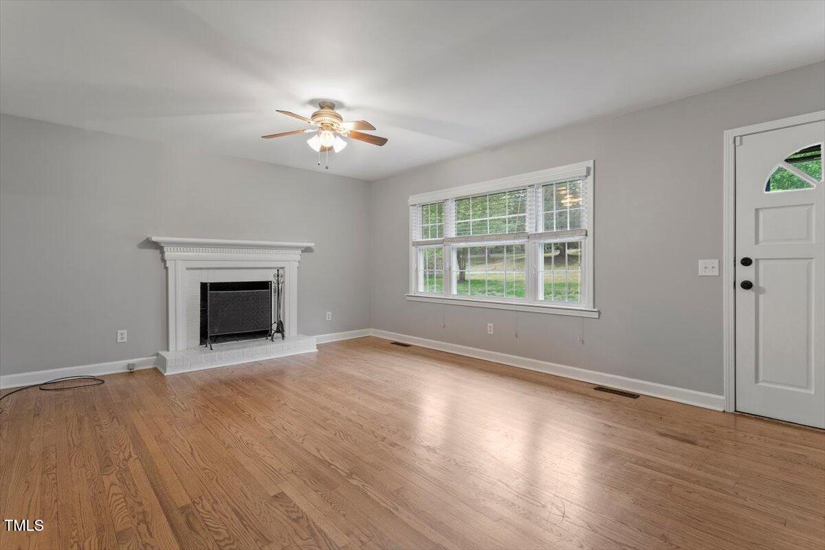 3402 Pat Tilley Road Bahama, NC 27503 - Photo 13 of 32 a view of an empty room with wooden floor fireplace and a window