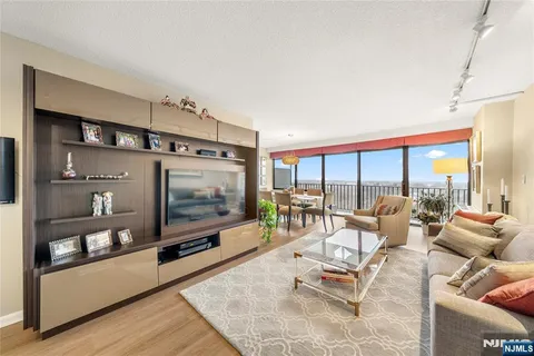 a living room with furniture a flat screen tv and a floor to ceiling window
