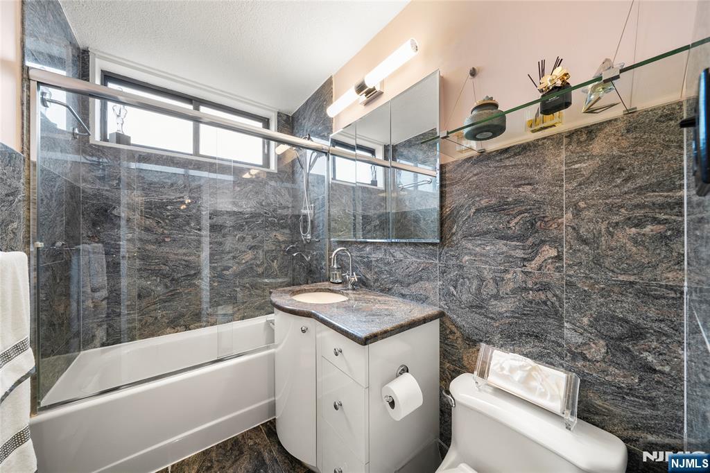 277 Prospect Avenue, Unit 14B Hackensack, NJ 07601 - Photo 14 of 23 a bathroom with a granite countertop sink a toilet and bathtub