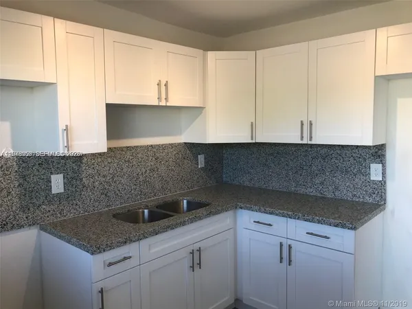 a kitchen with stainless steel appliances granite countertop a sink and a white cabinets