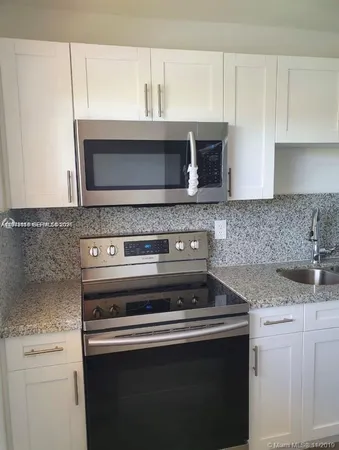 a kitchen with granite countertop a stove top oven microwave and cabinets