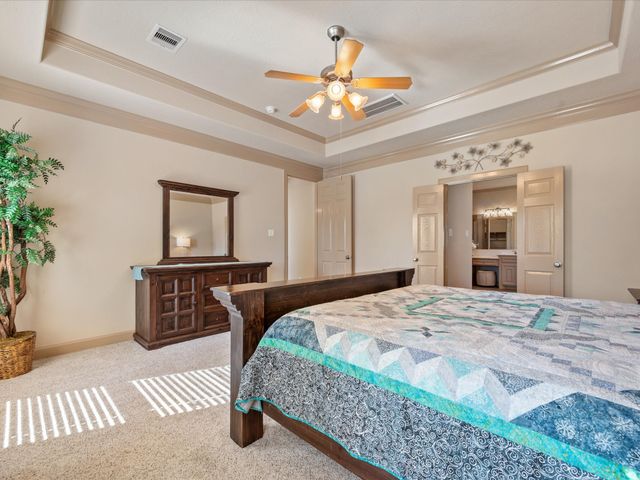 a bedroom with a large bed a chandelier and dresser
