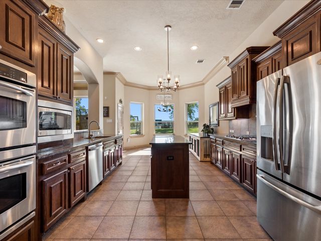 a large kitchen with stainless steel appliances kitchen island granite countertop a stove top oven a sink dishwasher a dining table and chairs with wooden floor