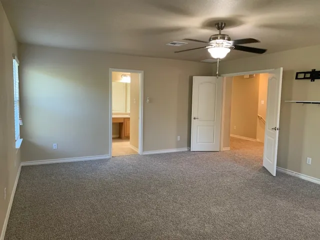 a view of an empty room with a chandelier fan