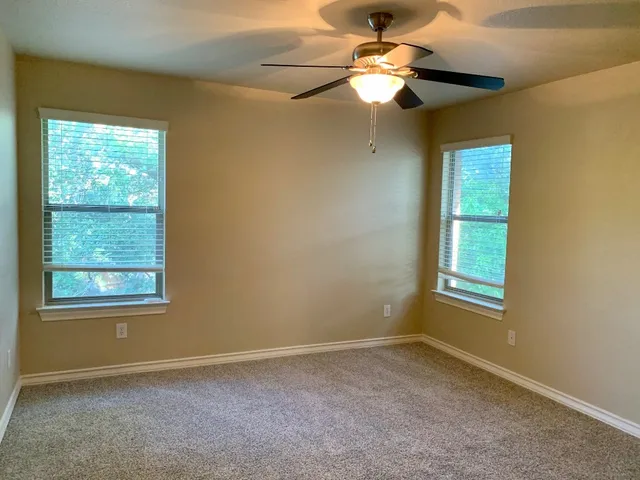 an empty room with windows and fan